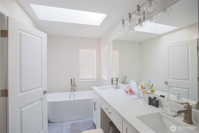 bathroom featuring a soaking tub, a skylight, and a sink