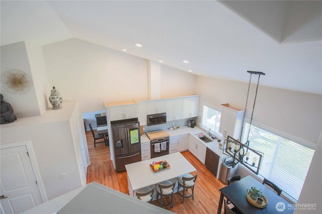 living area with recessed lighting, light wood-style floors, and high vaulted ceiling