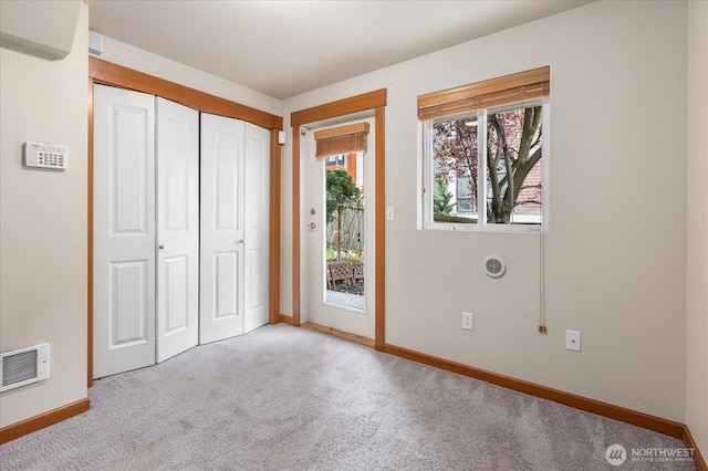 unfurnished bedroom featuring access to outside, carpet, visible vents, and baseboards