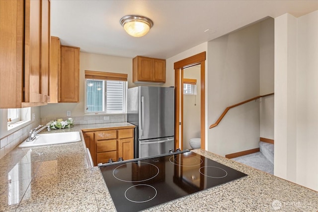 kitchen featuring tile countertops, a healthy amount of sunlight, freestanding refrigerator, and a sink