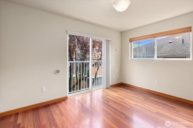 spare room with baseboards and wood finished floors