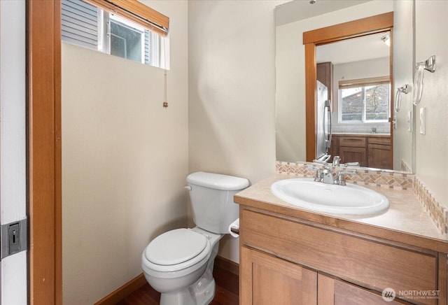 bathroom with backsplash, toilet, vanity, and baseboards