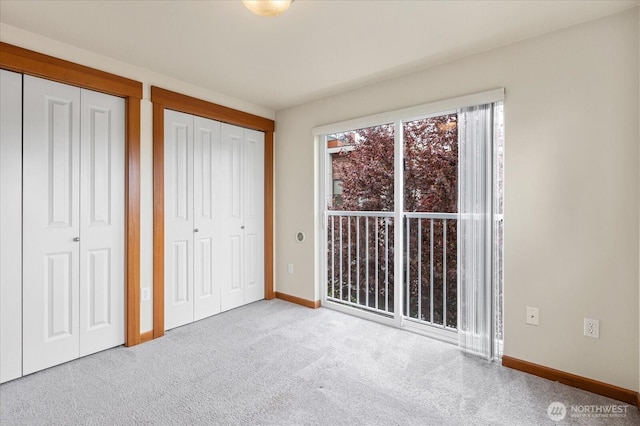 unfurnished bedroom featuring baseboards, carpet floors, and two closets