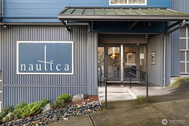 view of exterior entry with board and batten siding, metal roof, and a standing seam roof