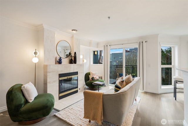 living area featuring light wood-style floors, a fireplace, and crown molding