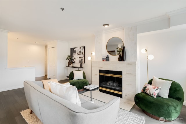 living room with a tiled fireplace, crown molding, baseboards, and wood finished floors