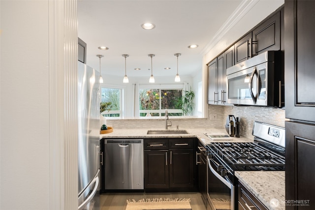 kitchen with a sink, light stone counters, decorative light fixtures, tasteful backsplash, and stainless steel appliances