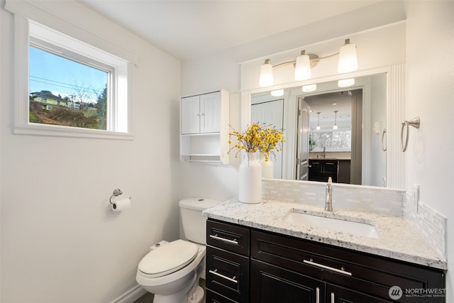 bathroom with vanity, toilet, and tasteful backsplash