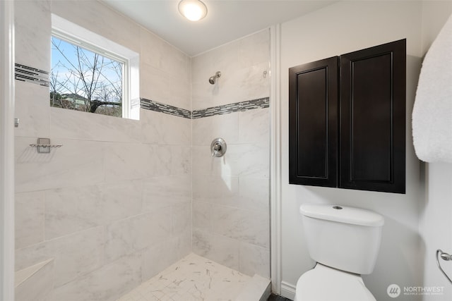 bathroom featuring tiled shower and toilet