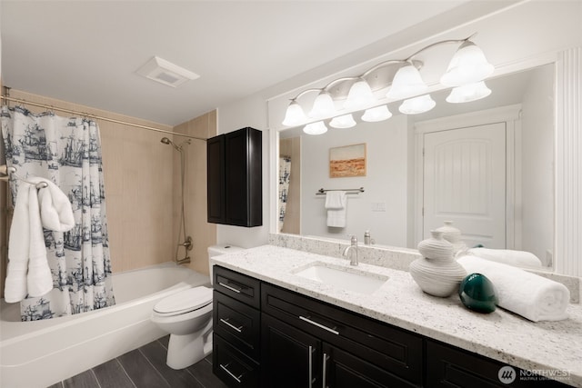 bathroom with visible vents, toilet, wood finished floors, shower / tub combo, and vanity