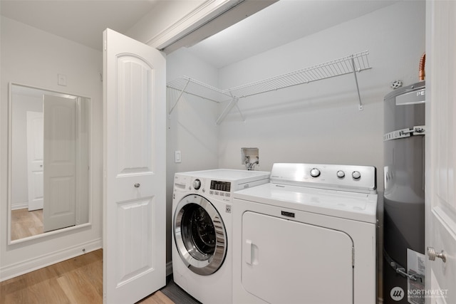 laundry room featuring water heater, laundry area, light wood-style flooring, and separate washer and dryer