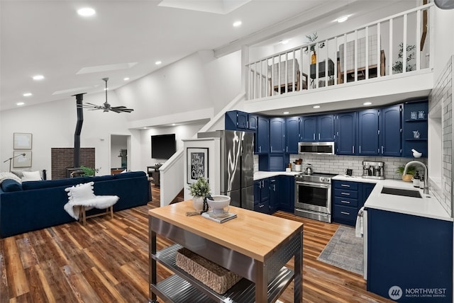 kitchen featuring a wood stove, a sink, stainless steel appliances, light countertops, and blue cabinets