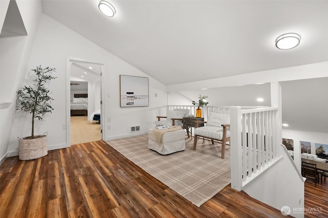 living area with lofted ceiling, wood finished floors, visible vents, and baseboards