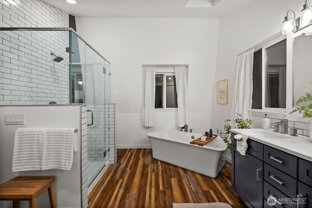 full bath featuring a soaking tub, a shower stall, vanity, and wood finished floors