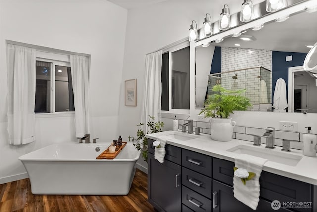 bathroom featuring a sink, a soaking tub, wood finished floors, and vaulted ceiling