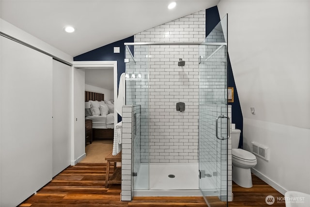 bathroom featuring visible vents, wood finished floors, connected bathroom, a shower stall, and vaulted ceiling