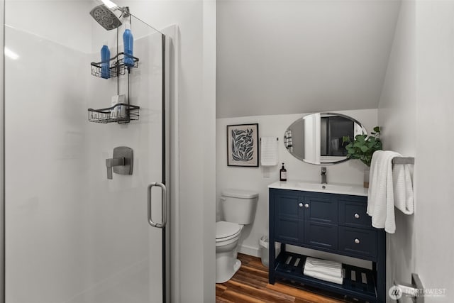 full bath with toilet, wood finished floors, a shower stall, lofted ceiling, and vanity