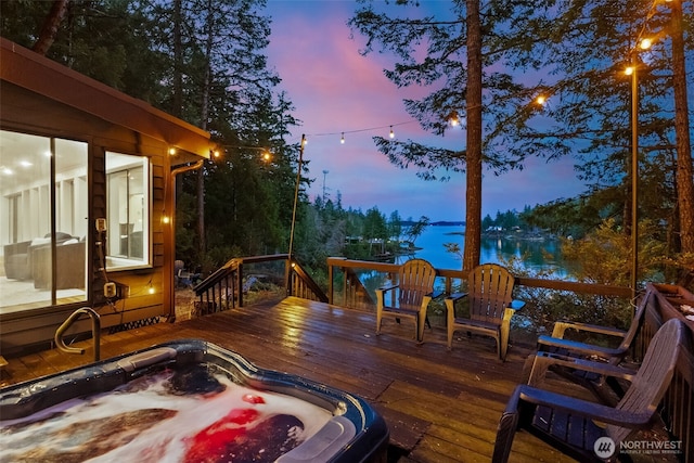 deck with hot tub deck surround and a water view