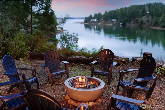 patio terrace at dusk with a water view and an outdoor fire pit