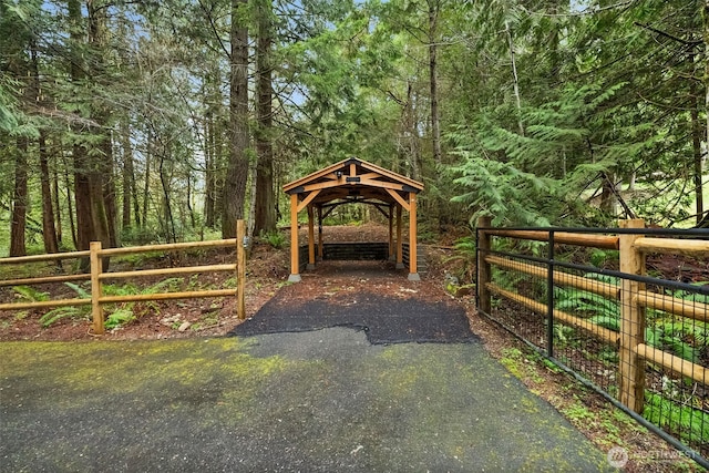 view of home's community featuring a detached carport, fence, a wooded view, and driveway