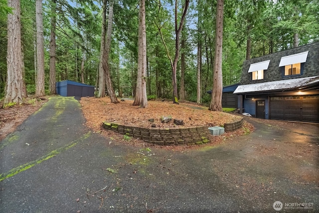 view of yard featuring an outdoor structure, a garage, and driveway