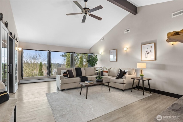 living area featuring visible vents, beamed ceiling, a baseboard heating unit, and light wood-style flooring