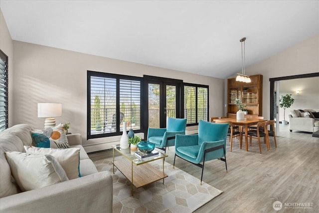 living room with lofted ceiling, plenty of natural light, light wood-style floors, and french doors