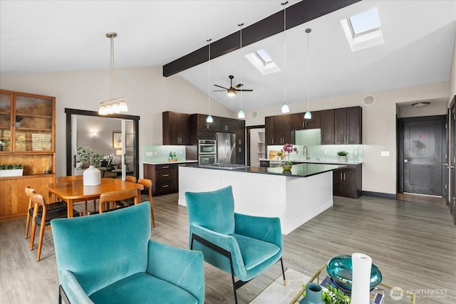 kitchen with light wood-style flooring, a center island, stainless steel appliances, dark brown cabinetry, and a skylight