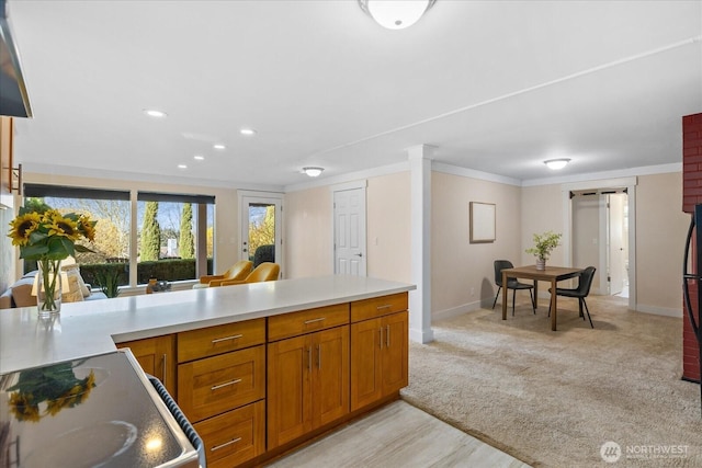 kitchen with light colored carpet, light countertops, electric range oven, ornamental molding, and brown cabinets