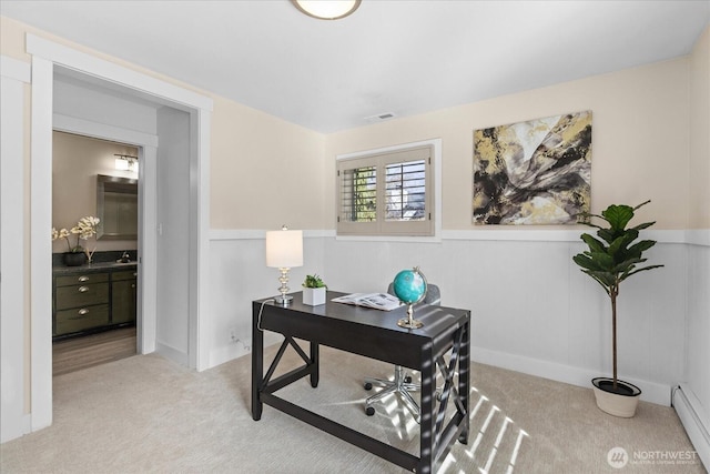 carpeted home office featuring a sink, visible vents, baseboard heating, and wainscoting