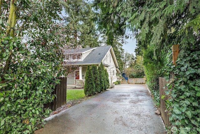 view of side of home with fence and a shingled roof