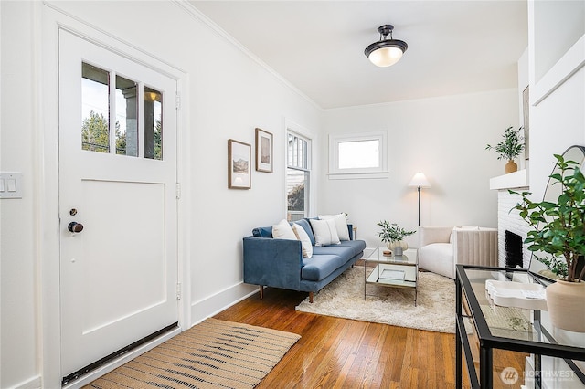 living room featuring baseboards, ornamental molding, a fireplace, and hardwood / wood-style flooring