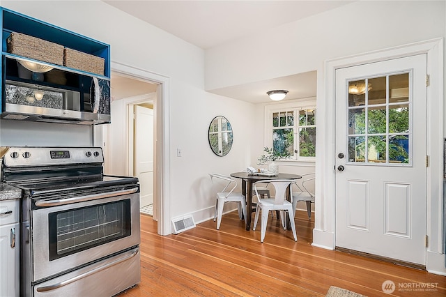 kitchen with stainless steel appliances, baseboards, visible vents, and light wood finished floors