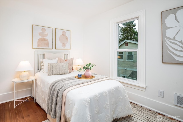 bedroom with visible vents, wood finished floors, and baseboards