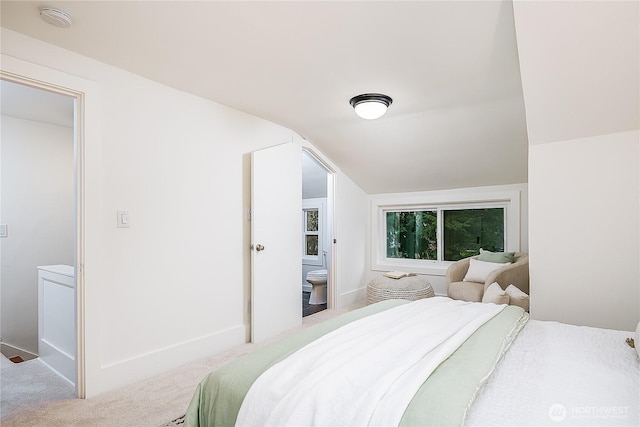 bedroom featuring vaulted ceiling, ensuite bathroom, baseboards, and carpet floors