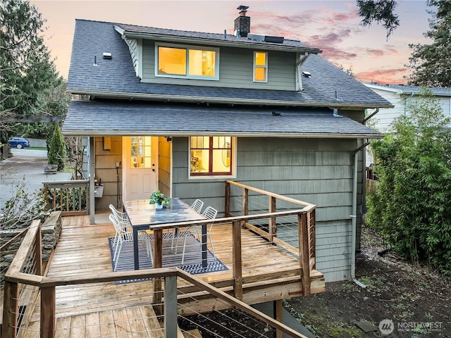 back of property with a deck, a chimney, and roof with shingles