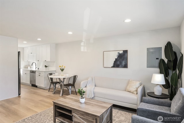 living room with electric panel, recessed lighting, and light wood finished floors