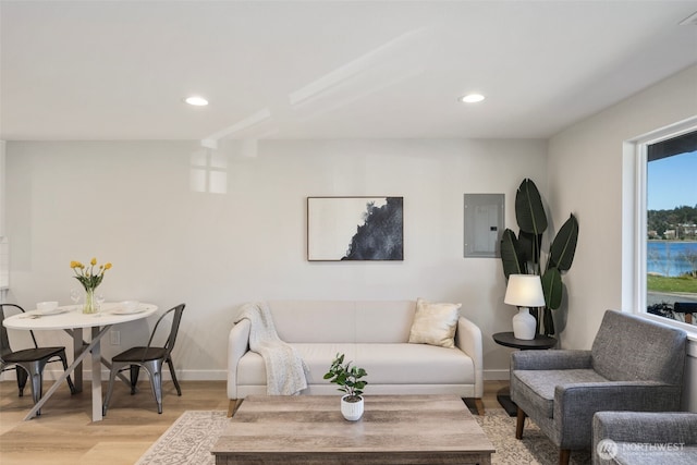 living room with visible vents, baseboards, light wood-style flooring, electric panel, and recessed lighting