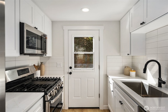 kitchen featuring a sink, tasteful backsplash, appliances with stainless steel finishes, and white cabinets