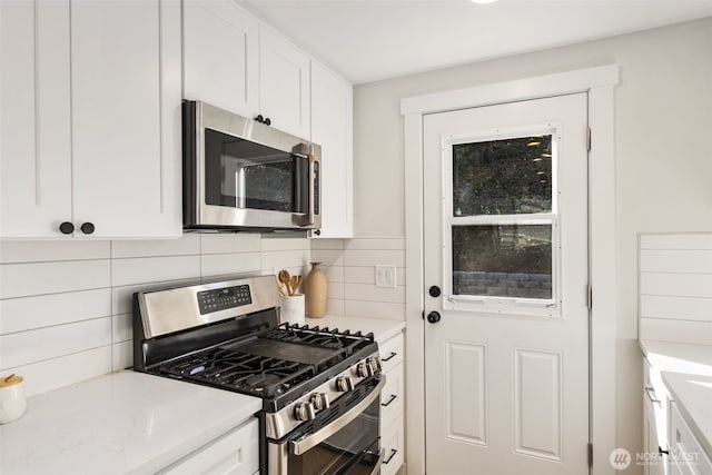 kitchen with backsplash, appliances with stainless steel finishes, and white cabinets