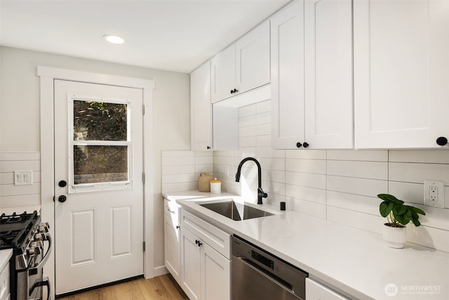 kitchen with a sink, light countertops, white cabinets, and stainless steel appliances