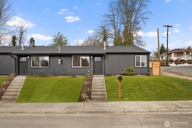 view of front of home featuring a chimney, a front yard, and a shingled roof