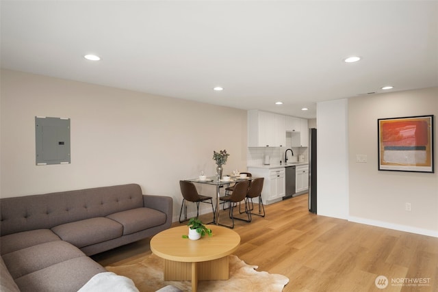 living room with electric panel, baseboards, light wood-style flooring, and recessed lighting