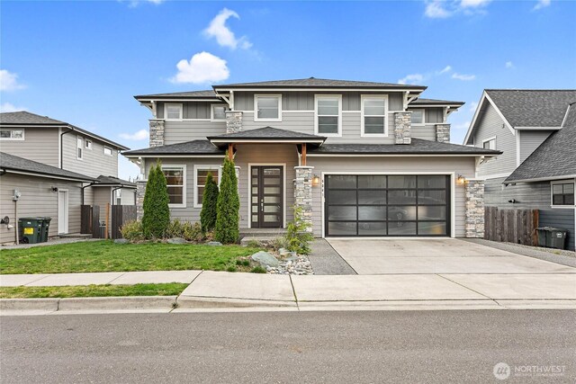 prairie-style home featuring a front lawn, fence, concrete driveway, an attached garage, and a shingled roof