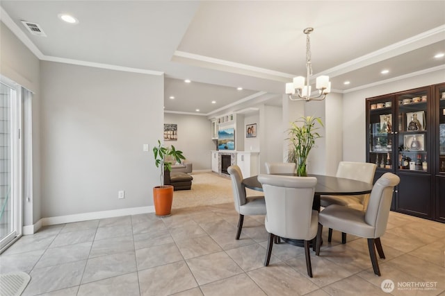 dining room featuring an inviting chandelier, visible vents, a raised ceiling, and ornamental molding