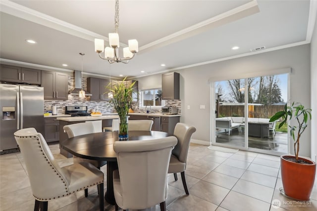 dining area with an inviting chandelier, a raised ceiling, crown molding, and a wealth of natural light