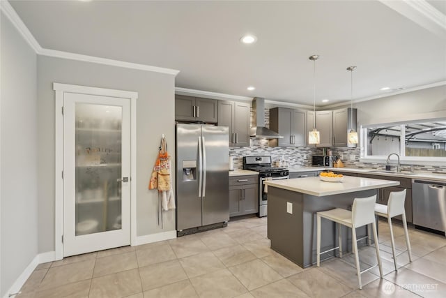 kitchen with a sink, stainless steel appliances, wall chimney exhaust hood, and ornamental molding