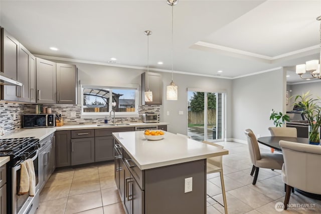 kitchen featuring stainless steel gas range oven, a kitchen bar, a wealth of natural light, and a sink