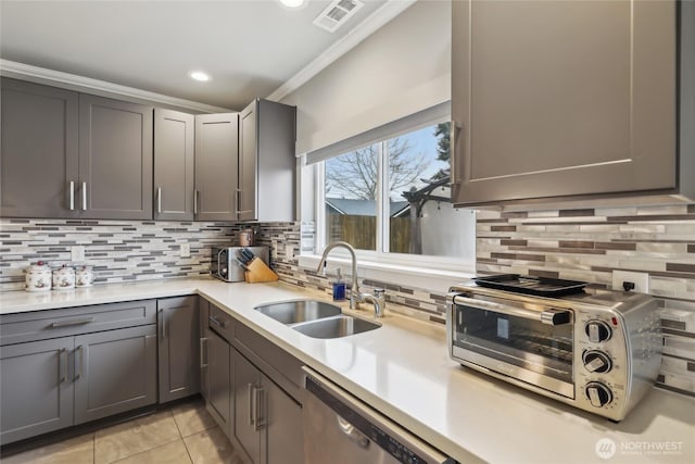 kitchen with light tile patterned floors, visible vents, a sink, light countertops, and stainless steel dishwasher