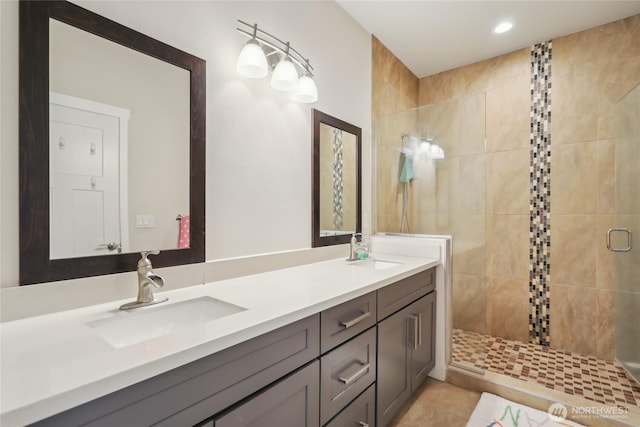 bathroom featuring double vanity, a stall shower, and a sink